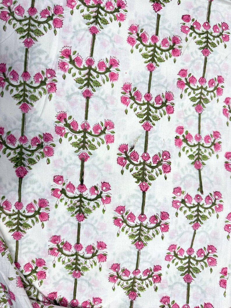 Pu&ograve; includere: Tessuto bianco con un motivo ripetuto di bouquet floreali rosa e steli verdi. Il motivo floreale &egrave; uniformemente distanziato, creando un motivo simmetrico. Il tessuto sembra essere di cotone o un materiale leggero simile, adatto a vari progetti.