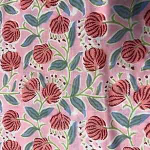 Pu&ograve; includere: Tessuto rosa con un motivo floreale ripetuto. Il design presenta grandi fiori stilizzati nei toni del rosso e del rosa, con steli verdi e foglie blu. Lo sfondo &egrave; rosa tenue.
