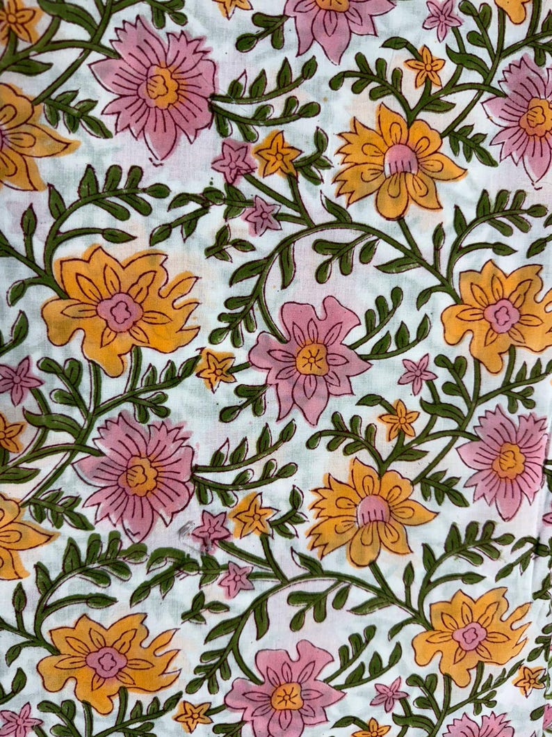Puede incluir: Una tela blanca con un patr&oacute;n floral repetitivo de flores grandes rosas y amarillas. El dise&ntilde;o incluye tallos y hojas de color verde oscuro que conectan las flores por toda la superficie, creando un estampado bot&aacute;nico denso.