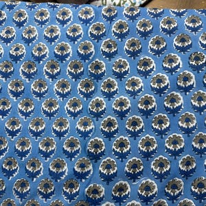 Pu&ograve; includere: Un tessuto blu con un motivo floreale ripetuto. I fiori sono grigi e bianchi con steli e foglie blu. Lo sfondo &egrave; azzurro. Questo tessuto &egrave; adatto per il patchwork, il cucito o altri progetti artigianali.