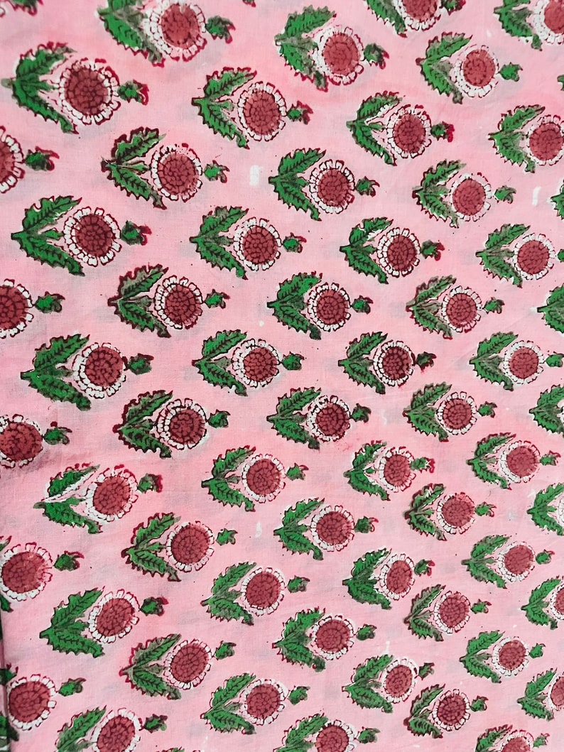Pu&ograve; includere: Tessuto rosa con un motivo ripetitivo di foglie verdi e fiori rossi e bianchi.
