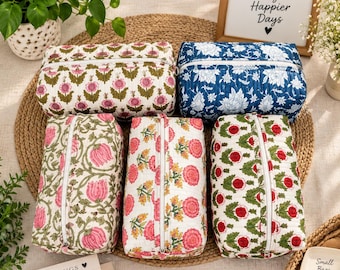Può includere: Cinque astucci rettangolari in tessuto trapuntato con cerniere bianche. Gli astucci presentano vari motivi floreali stampati in colori come rosa, verde, rosso e blu su sfondi bianchi o blu. Ogni astuccio ha una forma strutturata e squadrata.