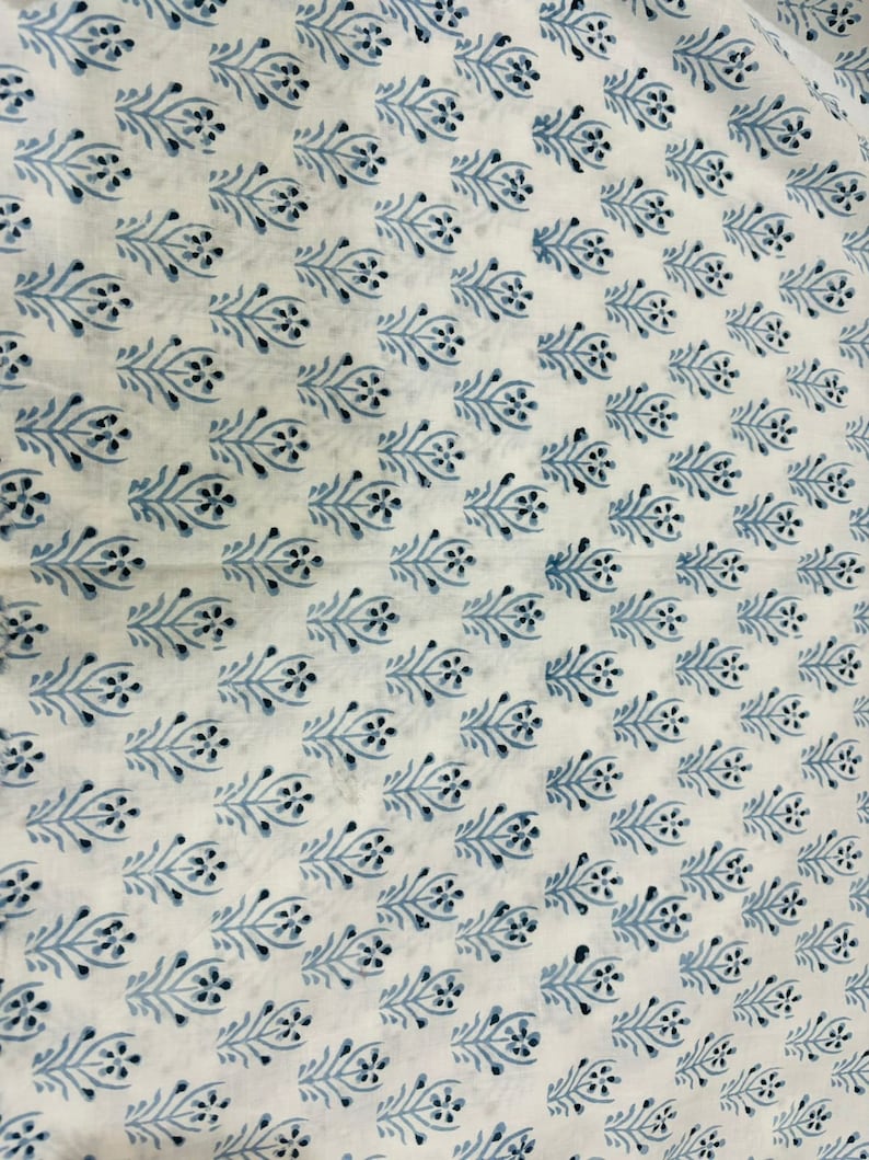 Pu&ograve; includere: Tessuto bianco con un motivo ripetitivo di piccoli ramoscelli fioriti blu. I ramoscelli sono stilizzati e hanno un design semplice ed elegante.
