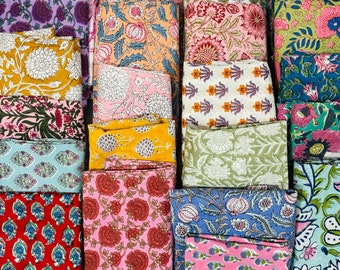 May include: A collection of colourful fabric squares with various floral patterns. The fabrics are arranged in rows and columns, creating a visually appealing display.
