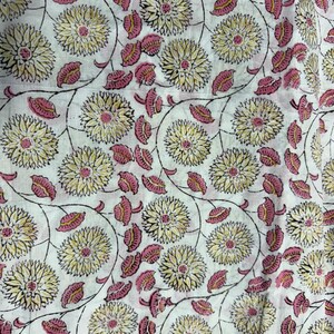 Pu&ograve; includere: Tessuto bianco con un motivo floreale ripetuto. Il design presenta grandi fiori gialli con centri rosa e foglie rosa, collegati da steli neri. L'estetica generale &egrave; in stile vintage e botanico.
