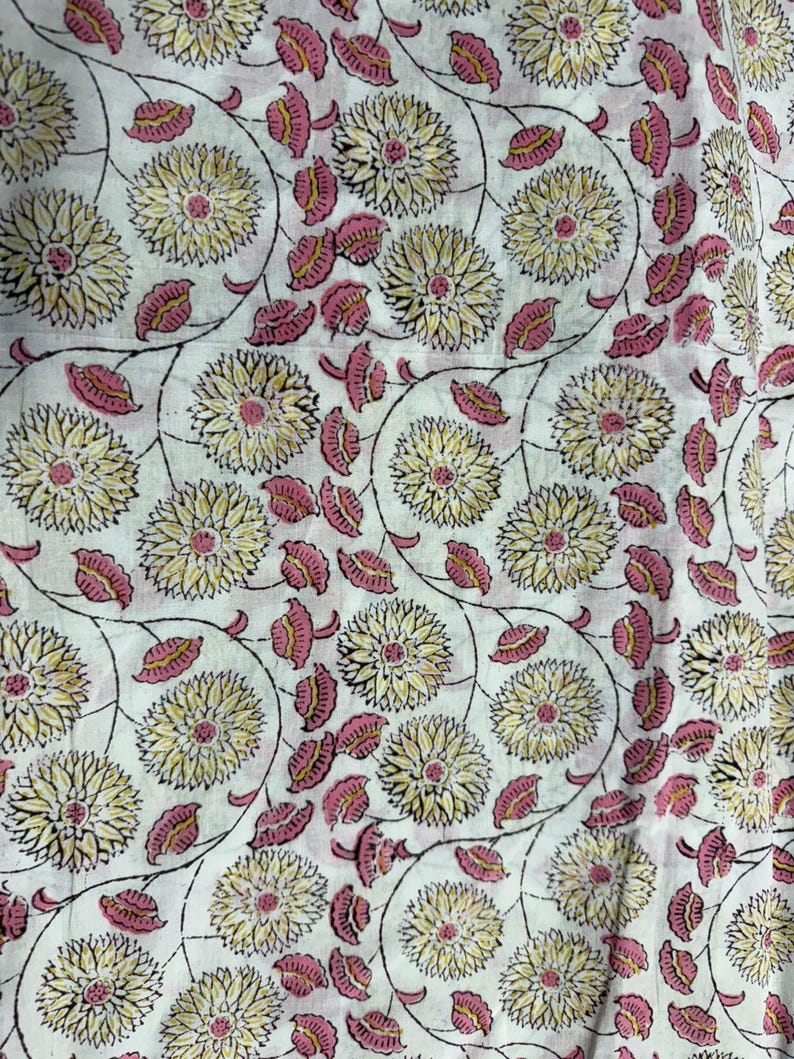 Pu&ograve; includere: Tessuto bianco con un motivo floreale ripetuto. Il design presenta grandi fiori gialli con centri rosa e foglie rosa, collegati da steli neri. L'estetica generale &egrave; in stile vintage e botanico.