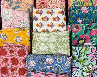 May include: A collection of colourful fabric squares with floral patterns. The fabrics are arranged in a grid pattern and feature a variety of colours, including pink, blue, green, yellow, and white.