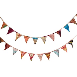 May include: Two strands of colorful pennant flags against a white background. The flags are triangular, made of patterned fabric in various colors like red, orange, blue, and green. The flags are strung together on a thin rope.