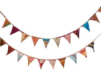 May include: Two strands of colorful pennant flags against a white background. The flags are triangular, made of patterned fabric in various colors like red, orange, blue, and green. The flags are strung together on a thin rope.