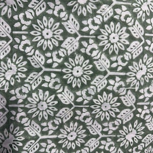Pu&ograve; includere: Primo piano di un tessuto con un motivo floreale ripetuto. Il design presenta fiori bianchi, foglie e forme geometriche su uno sfondo verde scuro. Il motivo &egrave; uniformemente distanziato e dettagliato.