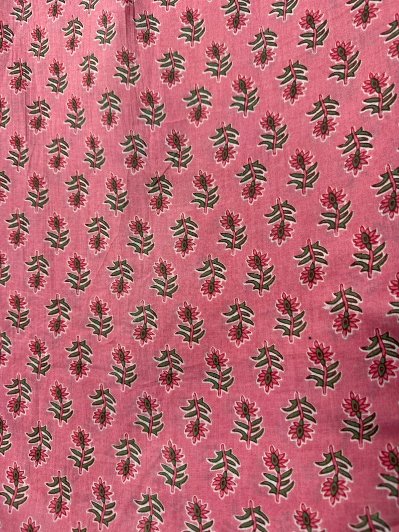 Puede incluir: Una tela rosa con un patr&oacute;n repetitivo de peque&ntilde;as flores estilizadas. Cada flor tiene p&eacute;talos de color rosa oscuro con un acento verde oscuro en el centro, conectadas a un tallo verde oscuro con hojas peque&ntilde;as, dispuestas en una cuadr&iacute;cula.