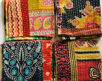 May include: Four stacks of colorful fabric squares with intricate patterns and stitching. The fabric is a mix of red, pink, yellow, blue, green, and black. The squares are arranged in two rows of two.