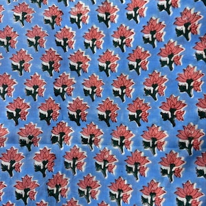 May include: A light blue fabric with a repeating pattern of pink lotus flowers and green leaves. The flowers are evenly spaced across the fabric, creating a visually appealing design. The fabric appears to be cotton or a similar material.