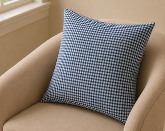 May include: A square throw pillow featuring a classic blue and white gingham check pattern. The fabric displays a consistent grid of small, alternating blue and white squares across the entire surface of the cushion, which is shaped as a square.