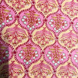 Pu&ograve; includere: Primo piano di un tessuto con un motivo floreale ripetuto. Il design presenta colori rosa, rosa chiaro e beige. Gli elementi floreali includono foglie e fiori stilizzati, creando un tessuto ornato e decorativo.