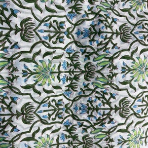 Puede incluir: Una tela blanca con un patr&oacute;n repetitivo de enredaderas y tallos de color verde oscuro. El dise&ntilde;o incluye motivos florales en verde claro y azul intercalados con peque&ntilde;as figuras de aves verdes, creando un estampado bot&aacute;nico sim&eacute;trico.