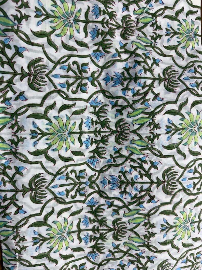 Puede incluir: Una tela blanca con un patr&oacute;n repetitivo de enredaderas y tallos de color verde oscuro. El dise&ntilde;o incluye motivos florales en verde claro y azul intercalados con peque&ntilde;as figuras de aves verdes, creando un estampado bot&aacute;nico sim&eacute;trico.
