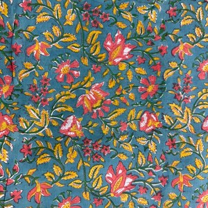 Pu&ograve; includere: Primo piano di un tessuto turchese con un motivo floreale. Il design presenta fiori rossi e gialli con foglie e viti verdi. I fiori hanno accenti bianchi e le foglie sono di un giallo brillante.