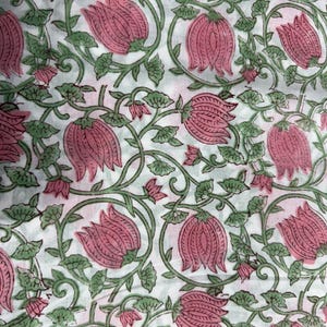 Puede incluir: Una tela blanca con un patr&oacute;n de estampado en bloque repetitivo de flores rosadas similares a lotos con tallos y hojas verdes. El dise&ntilde;o consiste en enredaderas interconectadas y motivos florales distribuidos uniformemente por la superficie.