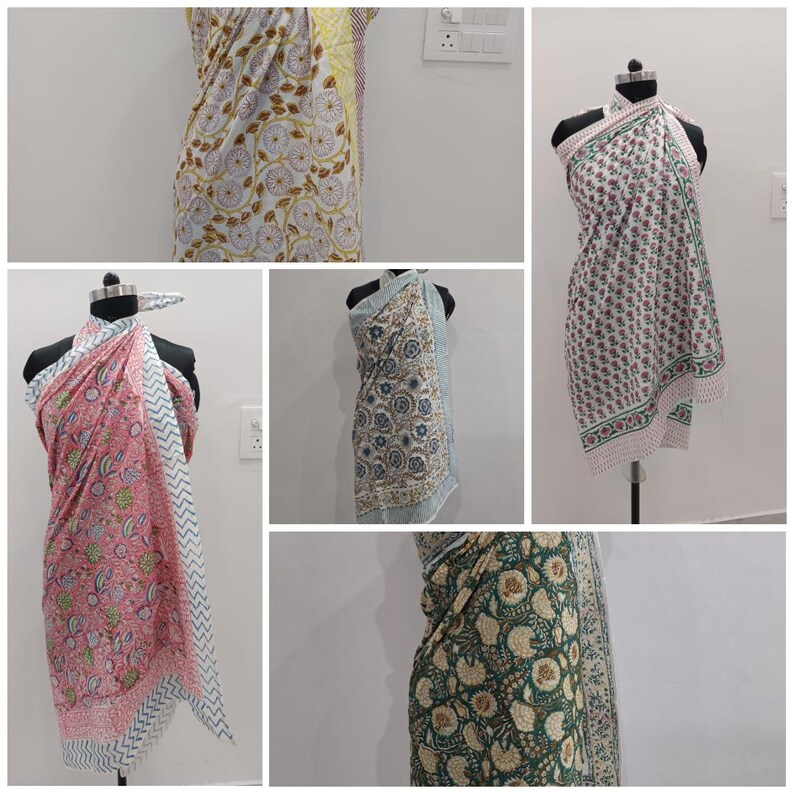 May include: Collection of colorful sarongs with floral patterns. The sarongs are displayed on mannequins, showcasing various designs. The colors include white, pink, green, blue, and yellow, with intricate floral and geometric prints. The sarongs are made of lightweight fabric.