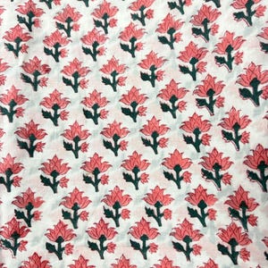 Pu&ograve; includere: Tessuto bianco con un motivo ripetuto di fiori rosa e steli verdi. I fiori sono stilizzati con pi&ugrave; petali e il motivo &egrave; uniformemente distribuito sul tessuto.