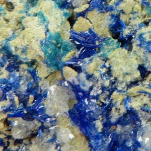 Könnte beinhalten: Nahaufnahme einer Gesteinsformation mit blauen und grünen Kristallen. Die Kristalle sind in eine hellbraune Matrix eingebettet.