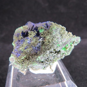 May include: Azurite and malachite mineral specimen with a blue and green colour pattern. The specimen is on a clear display stand.