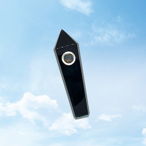 May include: A black crystal point with a round hole in the center. The crystal is pointed at the top and has a flat bottom. The crystal is against a blue sky background.