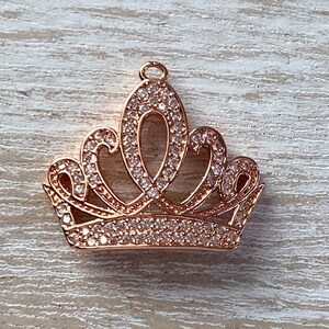 May include: A rose gold crown charm with clear rhinestones. The crown is a popular design for jewelry making.