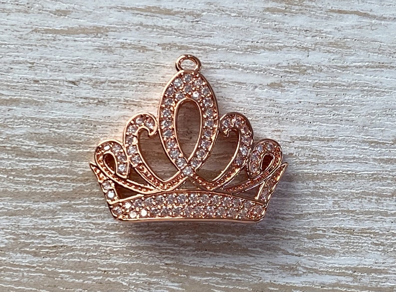 May include: A rose gold crown charm with clear rhinestones. The crown is a popular design for jewelry making.