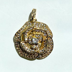 May include: A gold-tone pendant featuring a rose design with clear cubic zirconia stones.