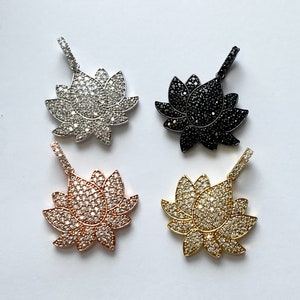 K&ouml;nnte beinhalten: Vier Lotusbl&uuml;ten-Anh&auml;nger mit Zirkonia-Steinen. Die Anh&auml;nger sind in Silber, Gold, Ros&eacute;gold und Schwarz.