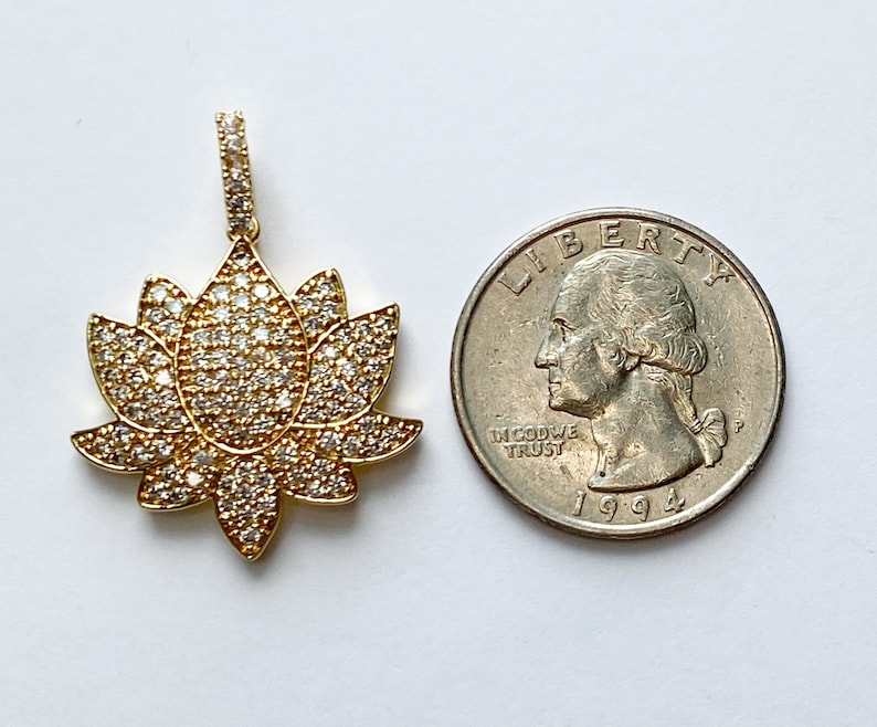 K&ouml;nnte beinhalten: Goldfarbener Lotusbl&uuml;tenanh&auml;nger mit klaren Zirkonia-Steinen. Der Anh&auml;nger ist etwa so gro&szlig; wie eine US-amerikanische 25-Cent-M&uuml;nze.