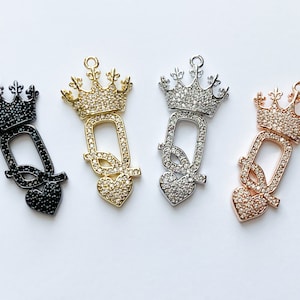 May include: Four charm pendants featuring a crown with a heart and the letter Q, each with a different finish: black, gold, silver, and rose gold.