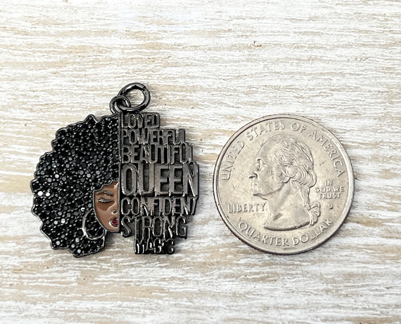 May include: Black metal charm with a silhouette of a woman with an afro and the words "Loved, Powerful, Beautiful, Queen, Confident, Strong, Magic" around her.