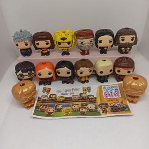 May include: A collection of fifteen small Harry Potter Funko Pop vinyl figures, including characters with various hair colours and outfits, arranged in two rows with a printed paper checklist featuring a QR code and character illustrations.