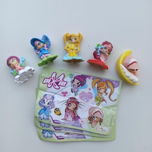Könnte beinhalten: Eine Sammlung farbenfroher Pixie-Figuren, jede mit einzigartigen Designs und Posen. Die Figuren befinden sich auf einer weißen Oberfläche, zusammen mit mehreren ungeöffneten Pixie-Verpackungen. Zu den Figuren gehören eine Fee auf einer Wolke, eine Fee in einem blauen Kleid und eine Fee auf einem Mond.