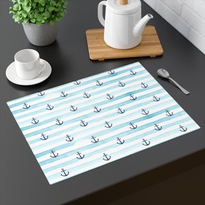 May include: A blue and white placemat with a repeating pattern of anchors. The placemat is made of a water-resistant material and is perfect for everyday use.