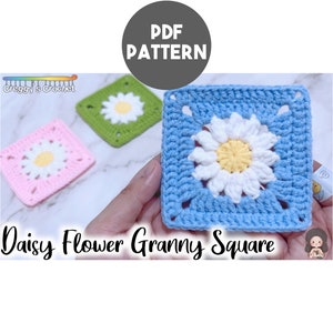 Puede incluir: Un patrón de crochet para un cuadrado de granny con una flor de margarita. El patrón incluye instrucciones para tejer un cuadrado con una flor de margarita en el centro. El cuadrado se muestra en azul, rosa y verde.