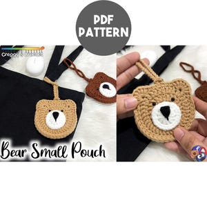 Op de afbeelding: Een gehaakte beertjesvormige tas met een bruin en wit gezicht. De tas is bevestigd aan een zwarte stoffen tas met een wit label waarop "Creggy's Crochet" staat. De afbeelding toont ook een close-up van de tas met een hand die hem vasthoudt.