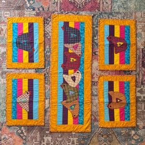 May include: A collection of six vibrant, quilted wall hangings. Each features a chicken applique on a striped background of blue, pink, purple, and yellow, with a gold border. The chickens are crafted from diverse patterned fabrics.