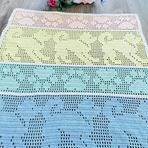 May include: A multi-colored crocheted baby blanket with a white border. The blanket is made in shades of pink, yellow, green, and blue.