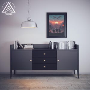 May include: A modern, dark gray sideboard with three drawers and two cabinet doors. A framed fantasy art print hangs above the sideboard, and a collection of books is displayed on top. A silver pendant light hangs from the ceiling. The text "FRAME NOT INCLUDED" is at the bottom.