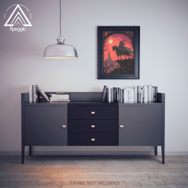 May include: A black framed print of a digital illustration of a person riding a horse in a dark forest with a red sky and a full moon. The print is hanging on a wall above a dark grey cabinet with three drawers and two doors.