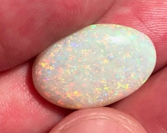 May include: A white opal gemstone with a pearlescent sheen and iridescent flashes of color.