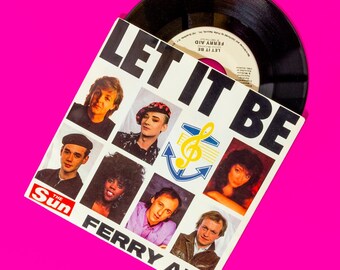 May include: A white vinyl record with a black label. The record is titled "Let It Be" and features a picture of a group of people. The record is part of the "Ferry Aid" charity project. The text "The Sun" is visible in the lower left corner.