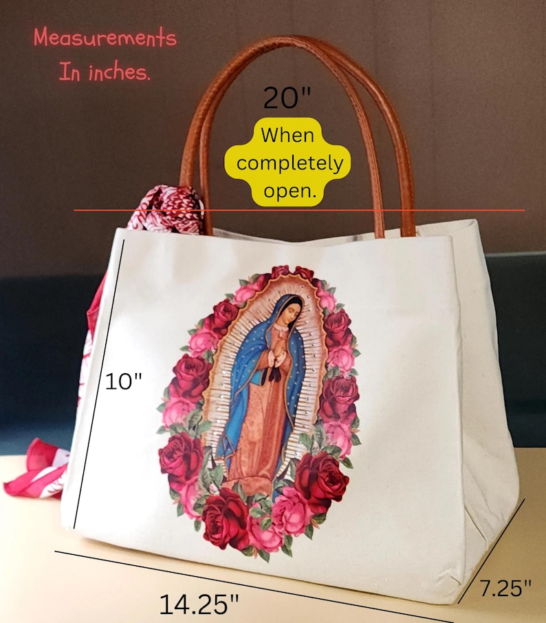 Puede incluir: Una bolsa de lona blanca con asa de cuero marr&oacute;n. La bolsa presenta una imagen colorida de la Virgen Mar&iacute;a rodeada de rosas rojas y rosas. La bolsa mide 10 pulgadas de alto, 14,25 pulgadas de ancho y 7,25 pulgadas de profundidad. Cuando est&aacute; completamente abierta, la bolsa mide 20 pulgadas de ancho.
