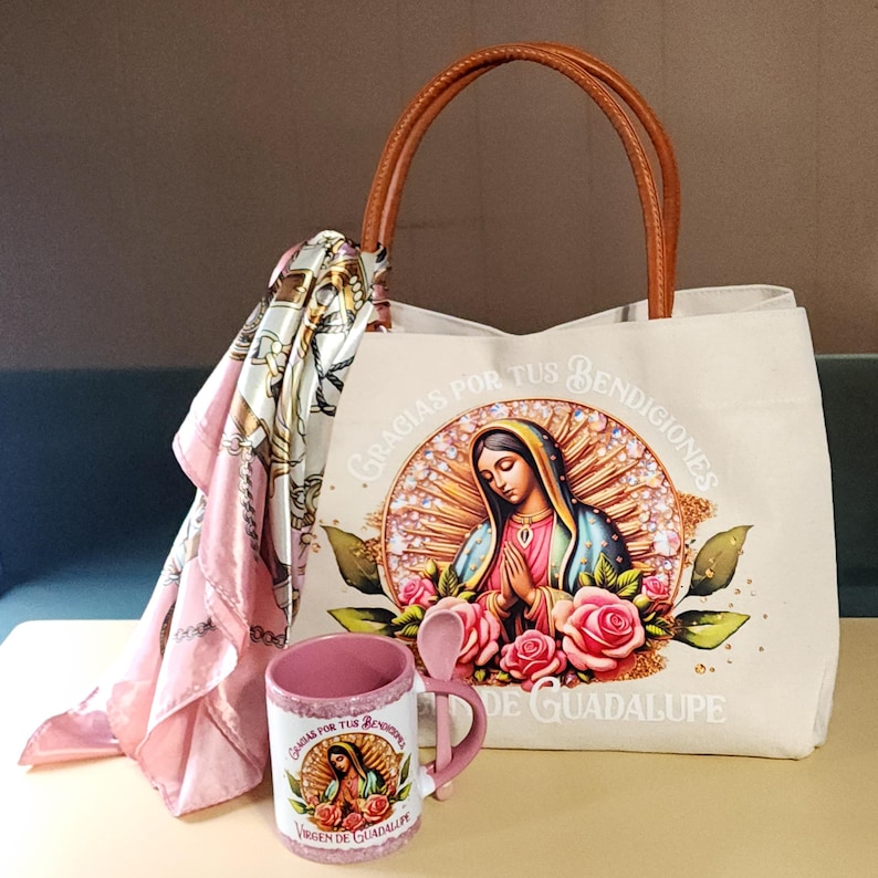 Puede incluir: Una bolsa de lona blanca con asas de cuero marr&oacute;n presenta una imagen colorida de la Virgen de Guadalupe. La bolsa incluye el texto "Gracias por tus bendiciones Virgen de Guadalupe". La imagen tambi&eacute;n incluye rosas rosas y un halo dorado. Una taza de cer&aacute;mica rosa con una cuchara y una bufanda de seda rosa tambi&eacute;n se incluyen en la imagen.
