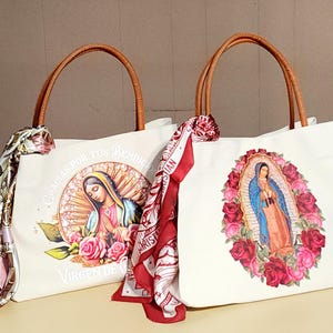 Puede incluir: Dos bolsas de lona blancas con asas de cuero marr&oacute;n. Una bolsa presenta una imagen colorida de la Virgen Mar&iacute;a con rosas. La otra bolsa presenta una imagen colorida de la Virgen Mar&iacute;a con rosas y el texto "Gracias por tus Bendiciones Virgen de Guadalupe".