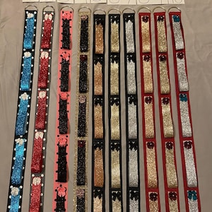 May include: Ten different ribbon strips with various colors and patterns, including black, red, gold, silver, and blue. Each strip has a small bow at the top and is numbered 1 through 10.